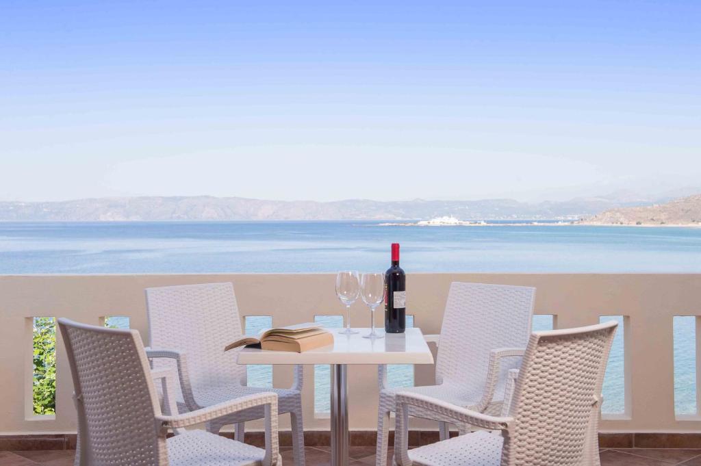 a white table with chairs and a bottle of wine at Balos Beach in Kissamos