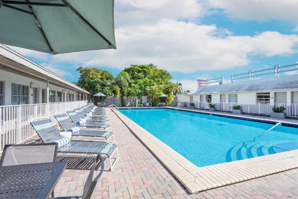 a swimming pool with chaise lounge chairs next to a building at Days Inn by Wyndham Miami Airport North in Miami