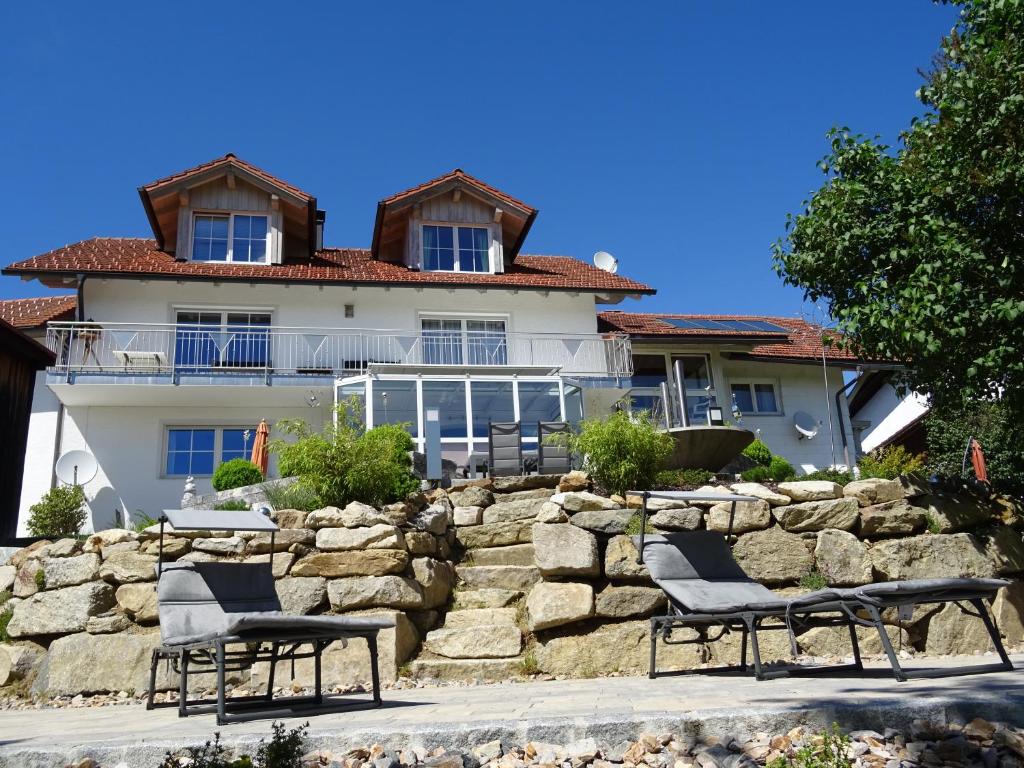 une maison avec un mur en pierre et des chaises devant elle dans l'établissement Fewo Gabi, à Neuschönau