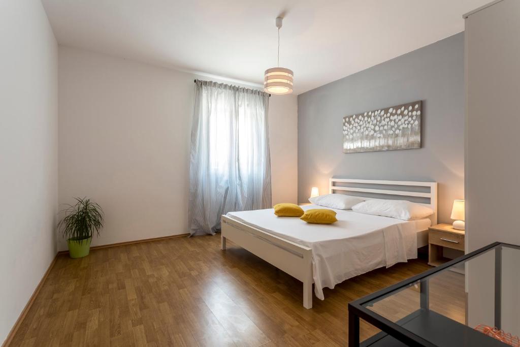 een slaapkamer met een wit bed met gele kussens erop bij Marijana Bol Apartments in Bol