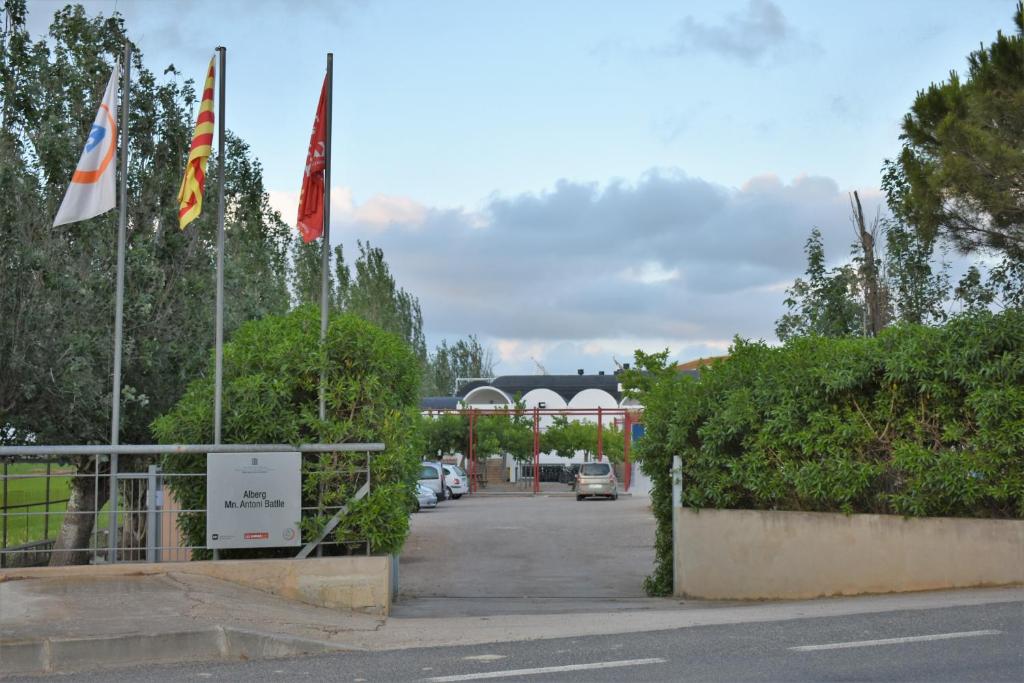 a parking lot with two flags in front of a building at Alberg Deltebre Xanascat in Deltebre