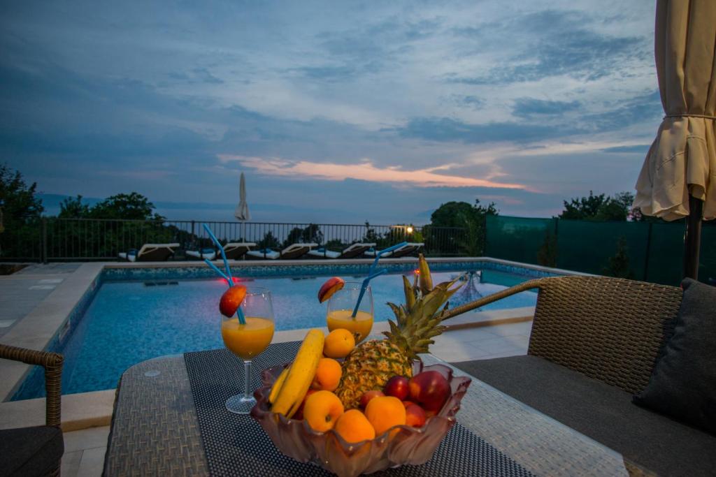 a bowl of fruit on a table next to a pool at Vila Divna in Podgora