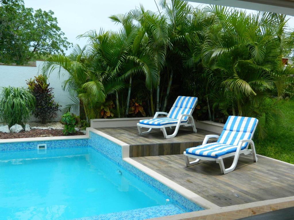 dos sillas azules y blancas sentadas junto a una piscina en Casa Kiin, en Chichimilá