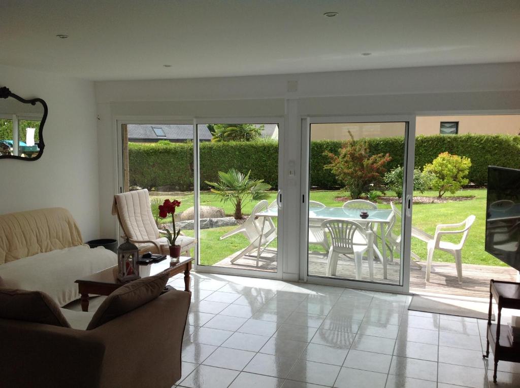 d'un salon avec une porte coulissante en verre menant à une terrasse. dans l'établissement La maison de Brijy, à Pleslin-Trigavou