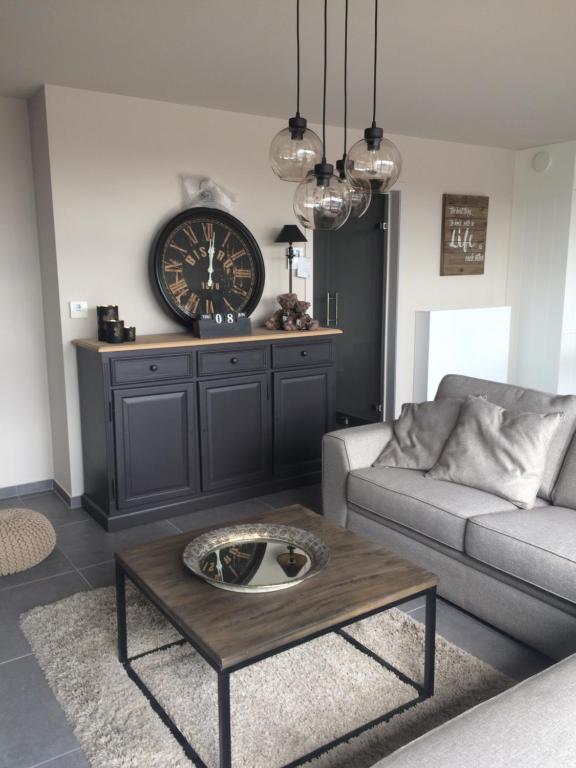 a living room with a coffee table and a clock at Maison Louise in Middelkerke