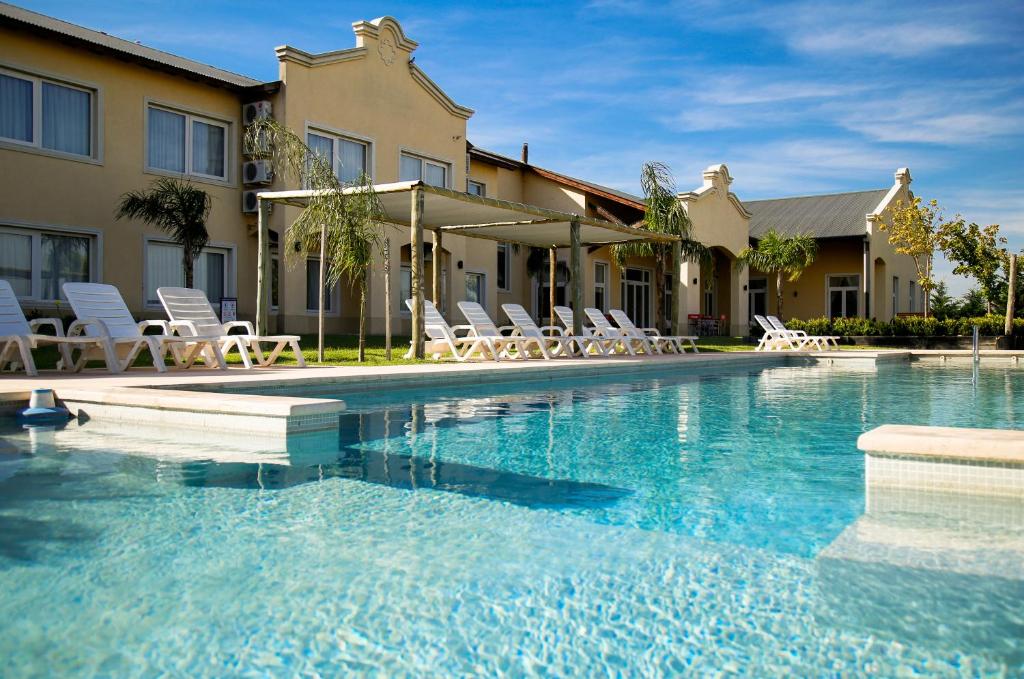 a swimming pool with white chairs and a building at Hotel Howard Johnson Trenque Lauquen in Trenque Lauquen