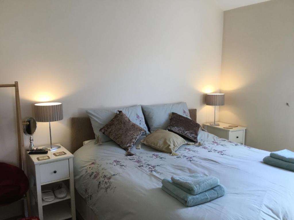 a bedroom with a white bed with pillows and two lamps at Canterbury Cottage in Prestatyn