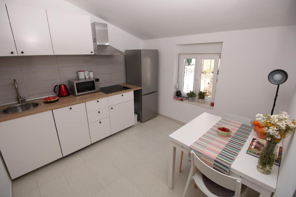 une cuisine avec des placards blancs et une table dans l'établissement Apartment Smokva ****, à Podgreben