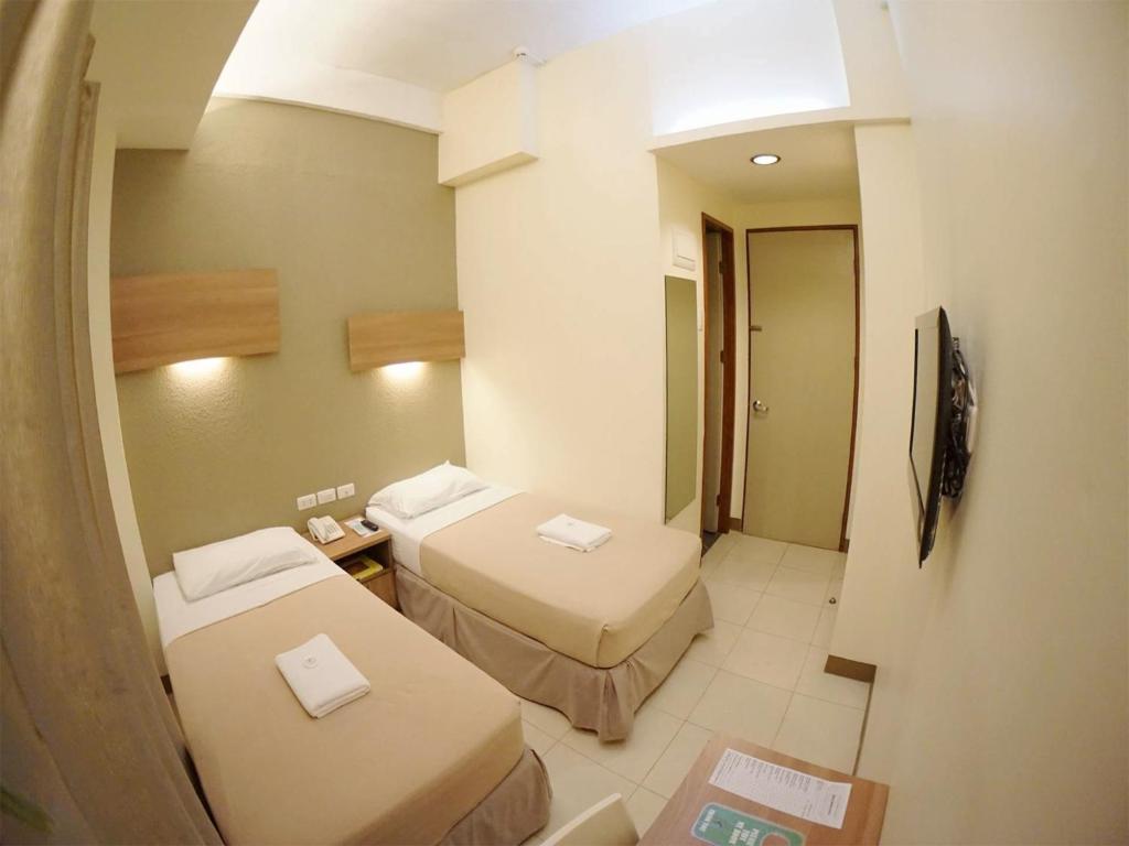 a small hotel room with two beds and a mirror at The Center Suites in Cebu City
