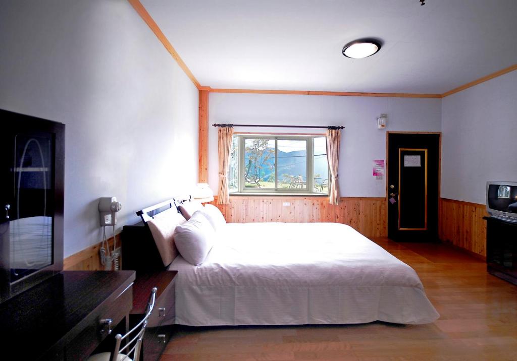 1 dormitorio con cama blanca y ventana en Winlu Vacation Farm en Renai