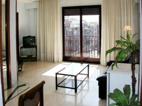 Apartamentos Olano C.B. في مدريد: غرفة معيشة مع أريكة وطاولة زجاجية