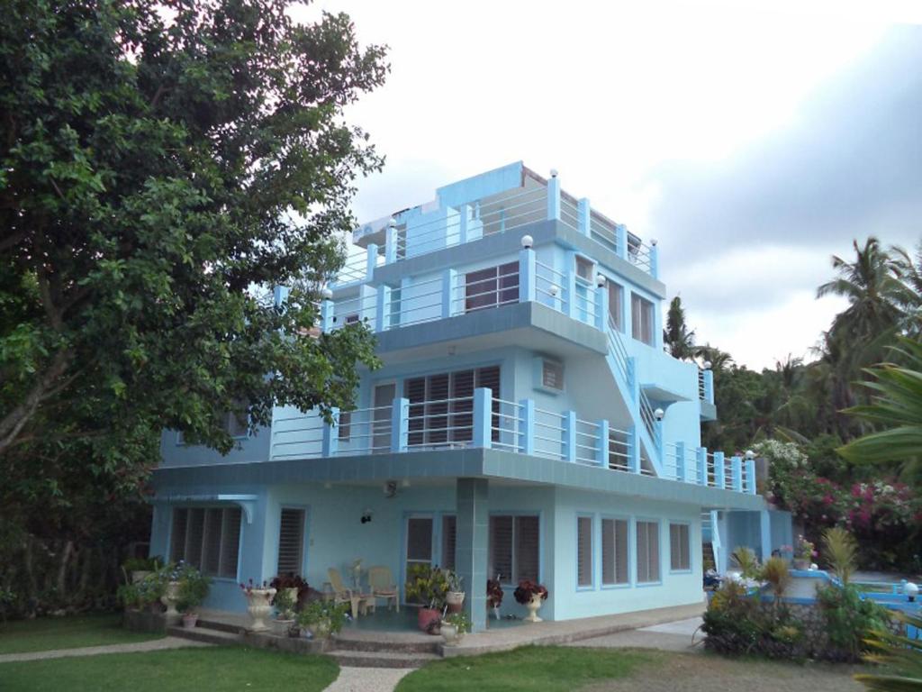 a blue building with a balcony and trees at High Steps Pension in Catmon