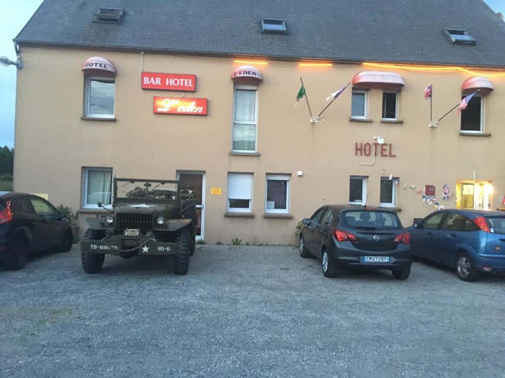 un bâtiment avec des voitures garées devant un hôtel dans l'établissement Hôtel l'Eden, à Brix