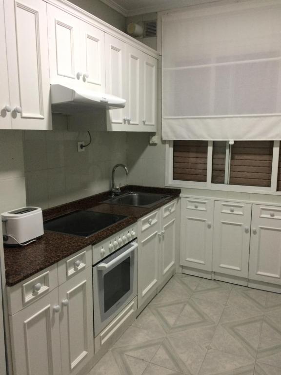 ヒホンにあるSagrado Corazonの白いキャビネットとシンク付きのキッチン