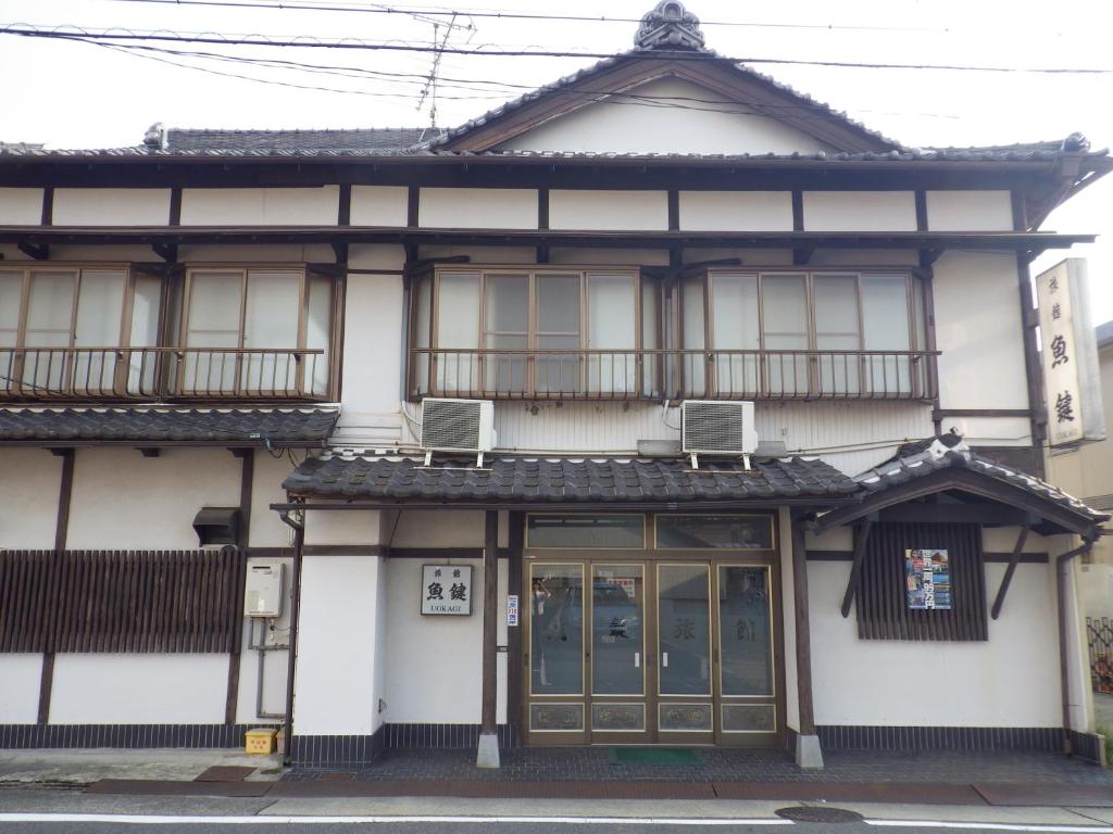 een wit gebouw met 2 balkons en 2 ramen bij Uokagi Ryokan in Nagoya