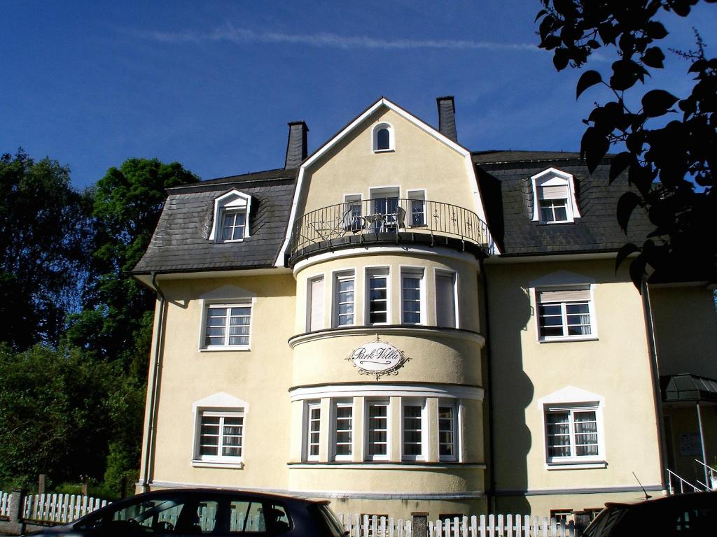 ein großes gelbes Haus mit Balkon darauf in der Unterkunft Park-Villa in Bad Steben