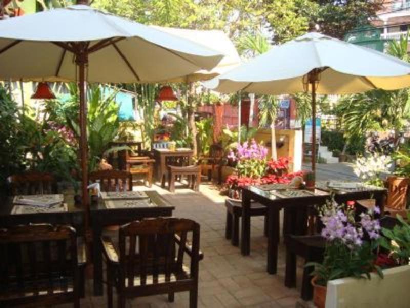 un patio con mesas, sillas y sombrillas en Thapae Gate Lodge, en Chiang Mai