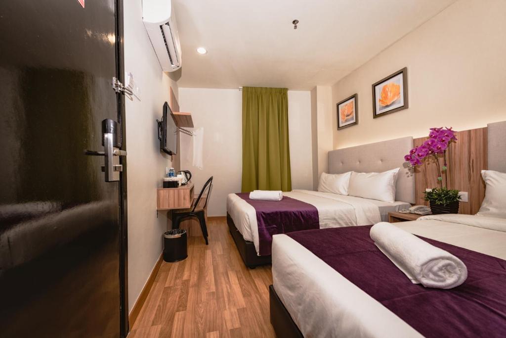 um quarto de hotel com duas camas com lençóis roxos em BIG M Hotel em Kuala Lumpur