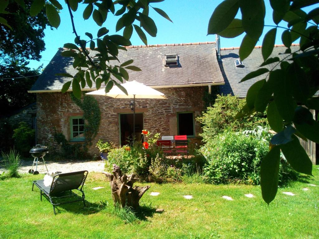 une maison en pierre avec une chaise et un parasol dans l'établissement Ar Parkou, à Plonévez-du-Faou
