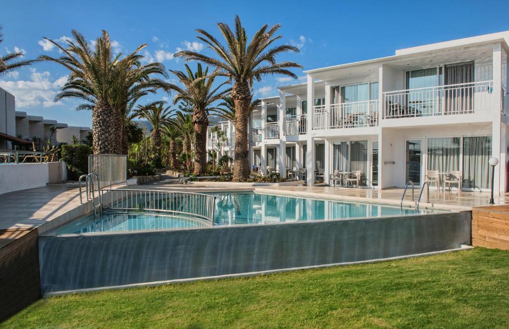 een groot huis met een zwembad en palmbomen bij Happy Days Beach Hotel in Georgioupolis