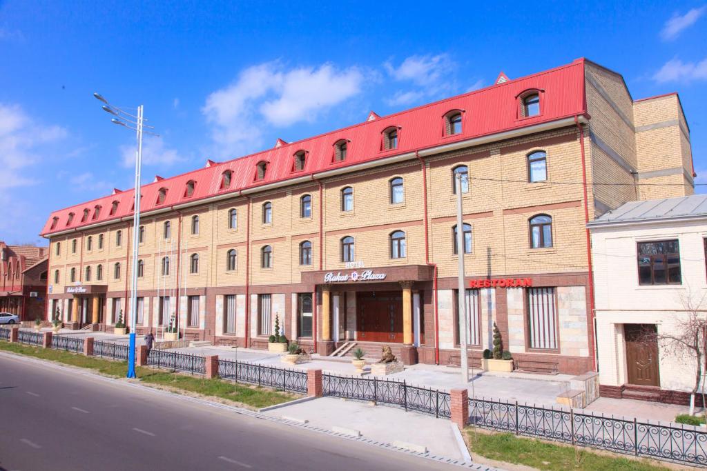 a large brick building with a red roof on a street at Rakat Plaza in Tashkent