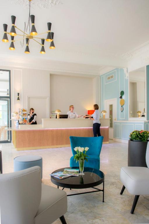 a woman standing in a lobby with a counter at Hôtel Miléade L'Orangeraie - Menton in Menton