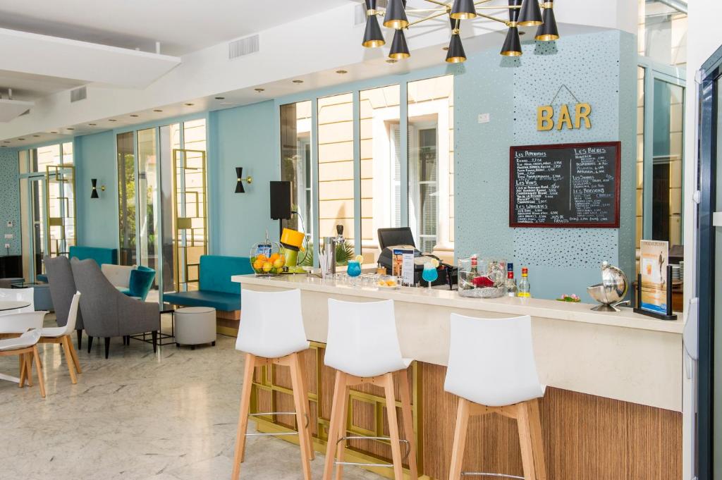 a bar in a restaurant with white stools at Hôtel Miléade L'Orangeraie - Menton in Menton