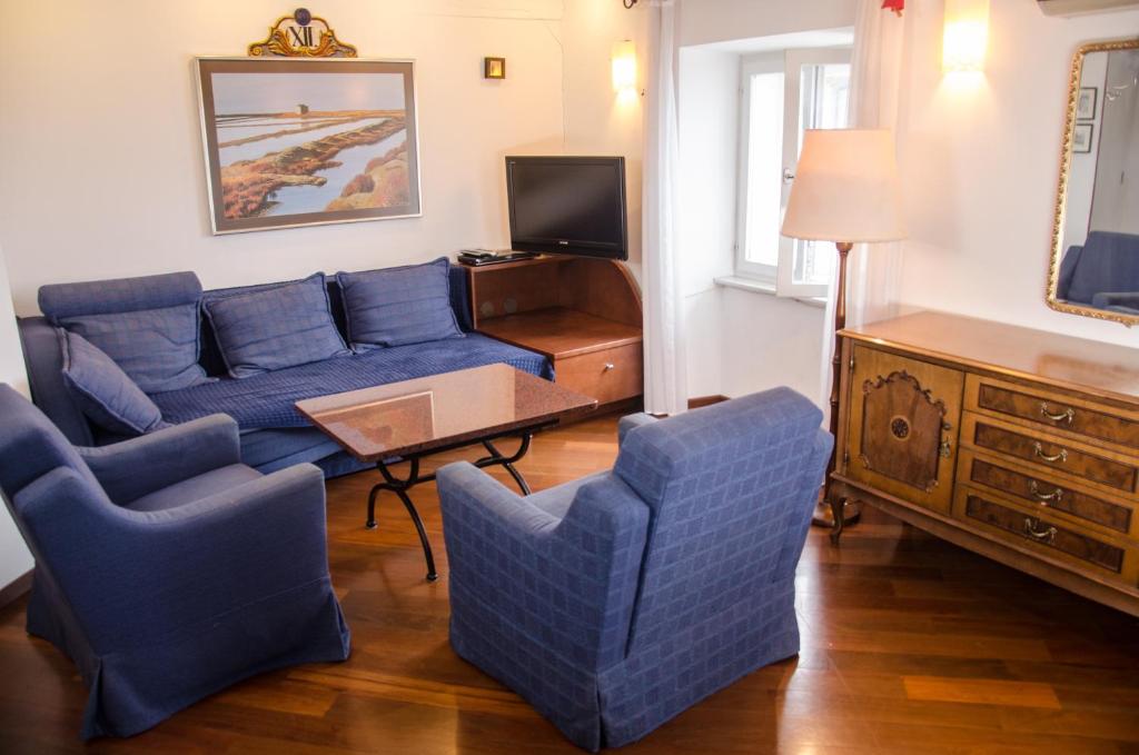 a living room with a blue couch and two chairs at Penthouse Presernovo nabrezje in Piran