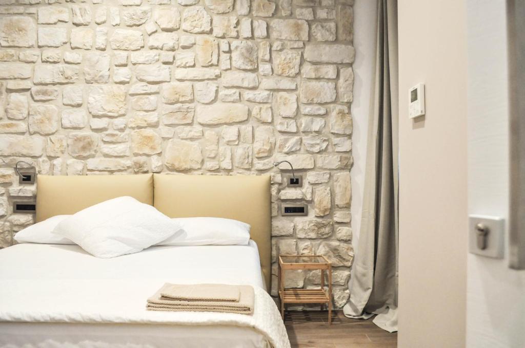 a bed in a room with a stone wall at Olivia Rooms Eurialo in Belvedere