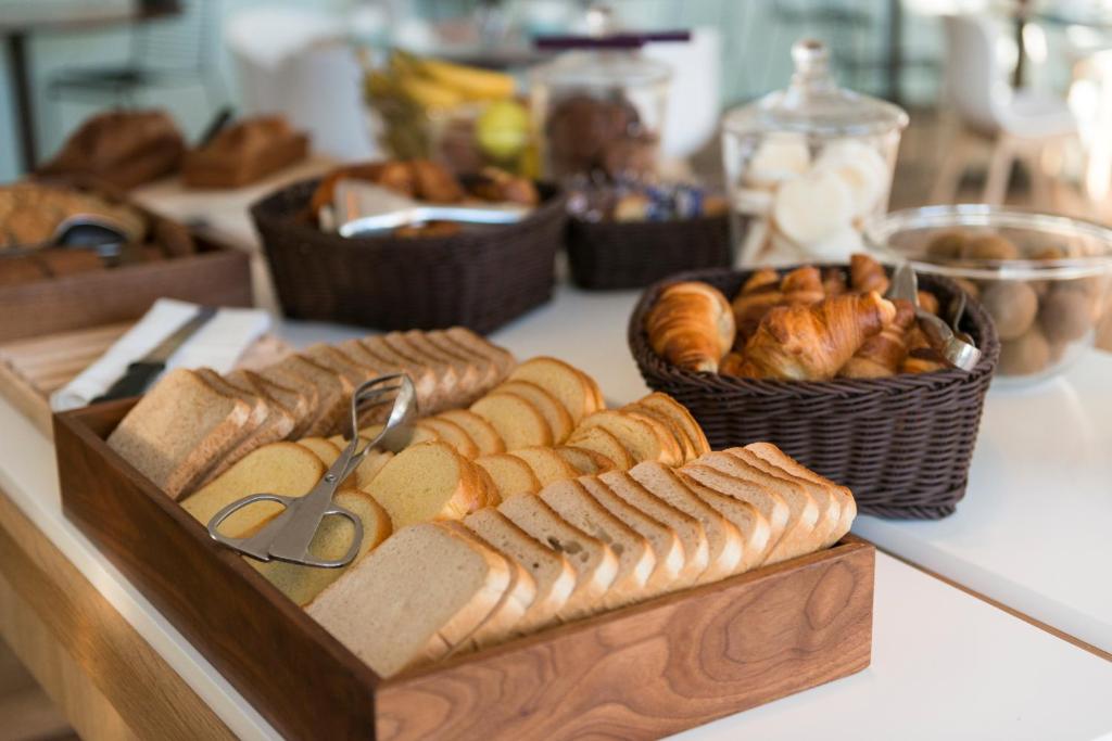a table with a tray of bread and pastries at Hôtel Miléade L'Orangeraie - Menton in Menton