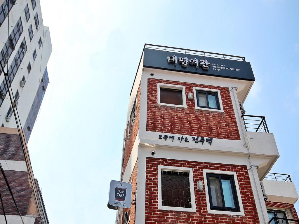 een hoog rood bakstenen gebouw met een bord erop bij Daemyung Guesthouse in Jeonju