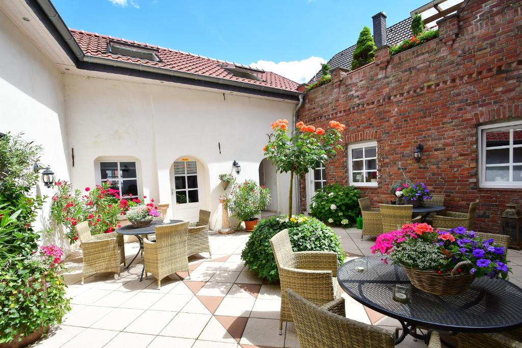 un patio al aire libre con mesas, sillas y flores en Ferienhaus Burgblick Brueggen, en Brüggen