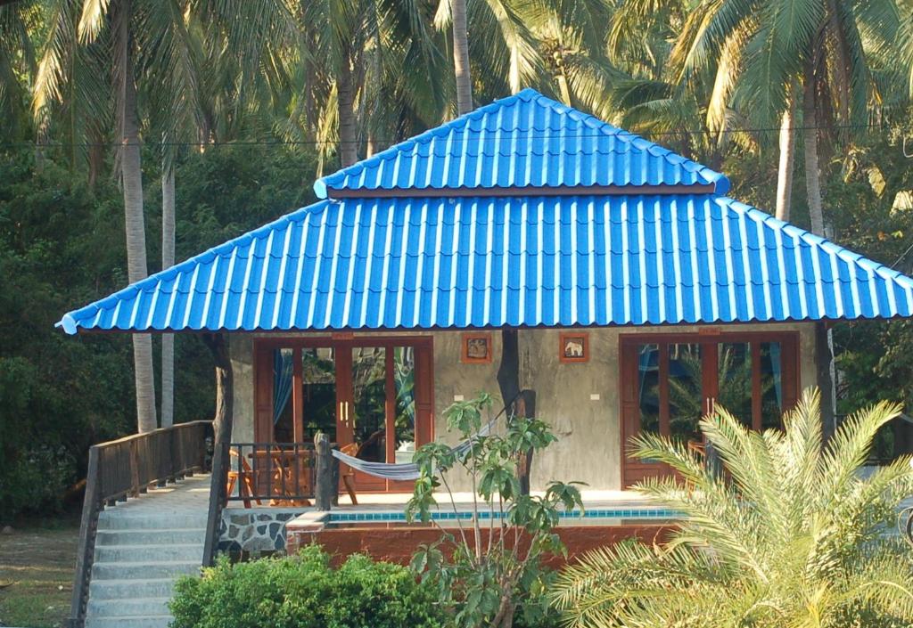 a small house with a blue roof and stairs at Wonderland Healing Center in Thongsala
