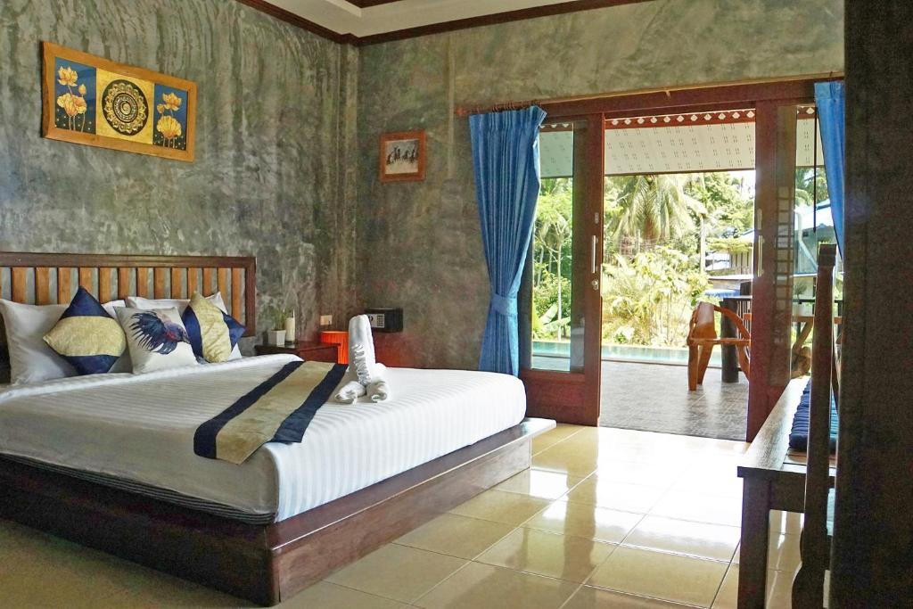 a bedroom with a bed and a sliding glass door at Wonderland Healing Center in Thongsala