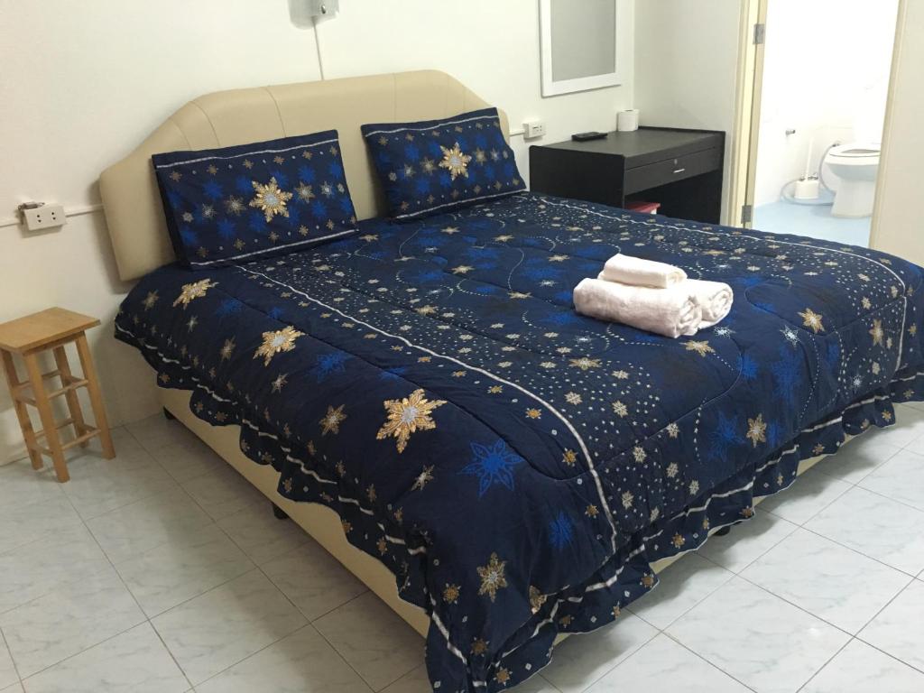 a bed with a blue comforter with two towels on it at Happy Home Guest House in Ban Phe