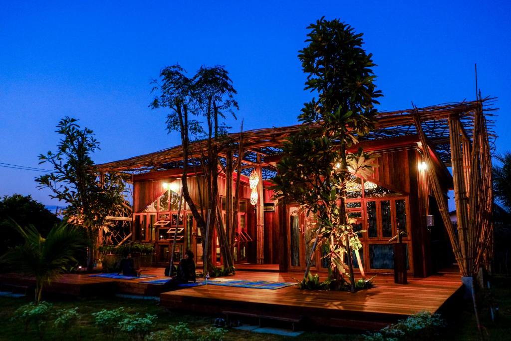 uma casa com um deque de madeira à noite em Baangaimuan em Lamphun