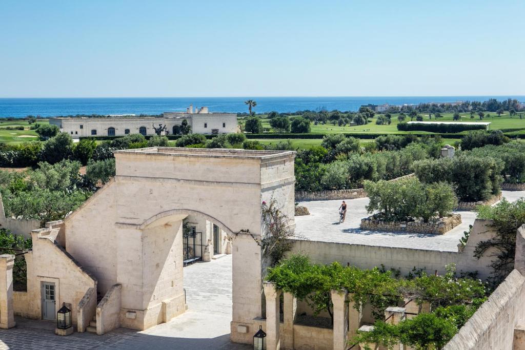 een extern uitzicht op een gebouw met een boog en bomen bij Borgo Egnazia in Savelletri di Fasano