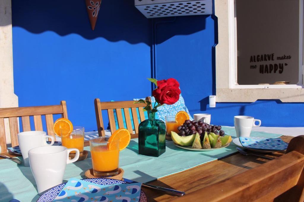 阿爾布費拉的住宿－Casa Mar Azul，一张桌子,上面有果盘和玫瑰花瓶