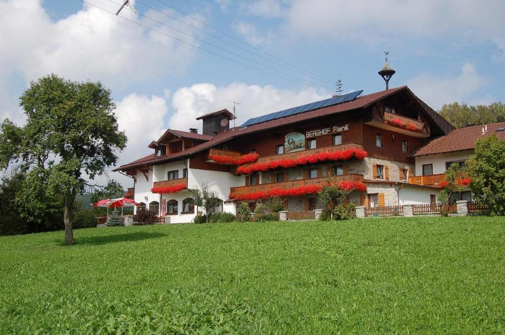 un gran edificio con flores rojas a un lado. en Berghof Pension und Ferienwohnungen, en Bischofsmais