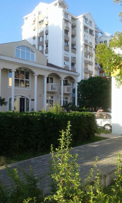 a large white building with bushes in front of it at Dena apartman Tivat in Tivat