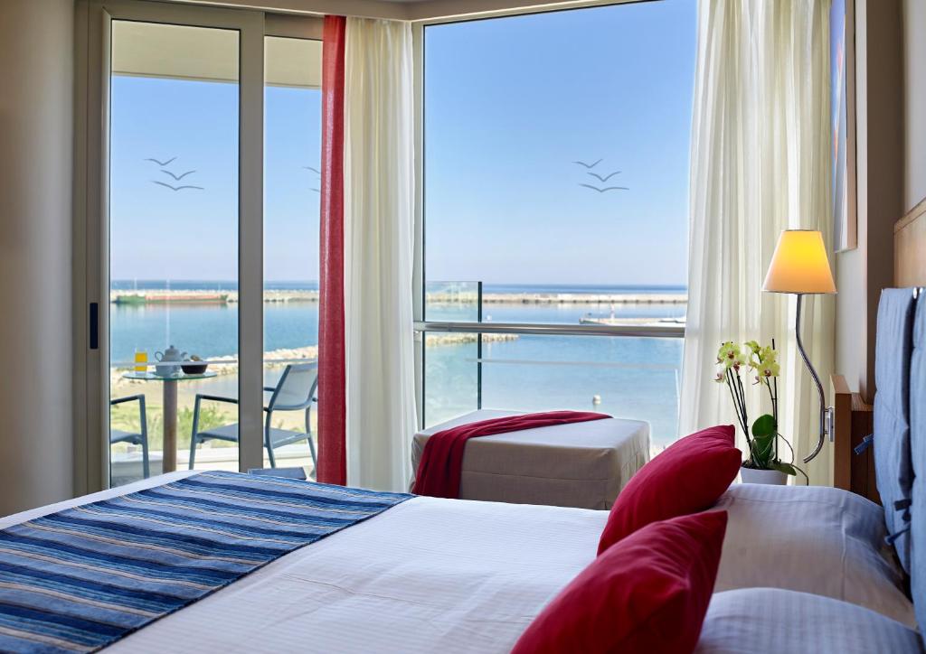 a hotel room with a bed and a view of the ocean at Kyma Suites Beach Hotel in Rethymno