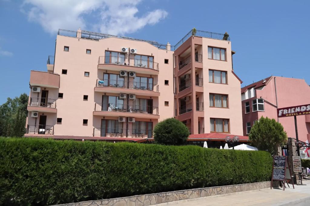 a pink building with bushes in front of it at Friends Family Hotel in Sunny Beach