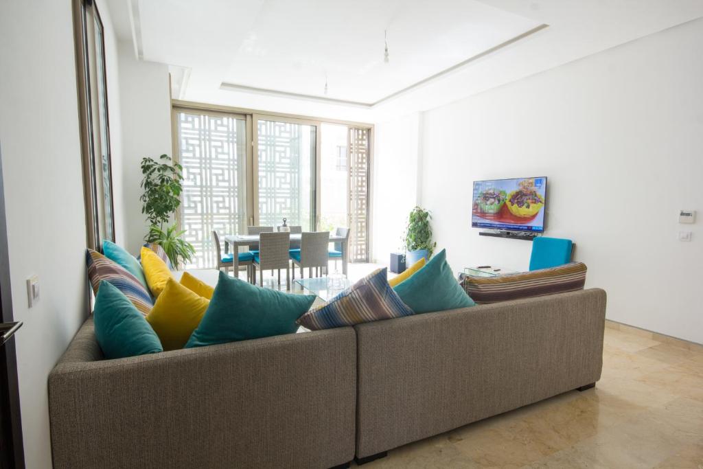Marina Rabat Suites & Apartments في ساليه: غرفة معيشة مع أريكة مع وسائد ملونة