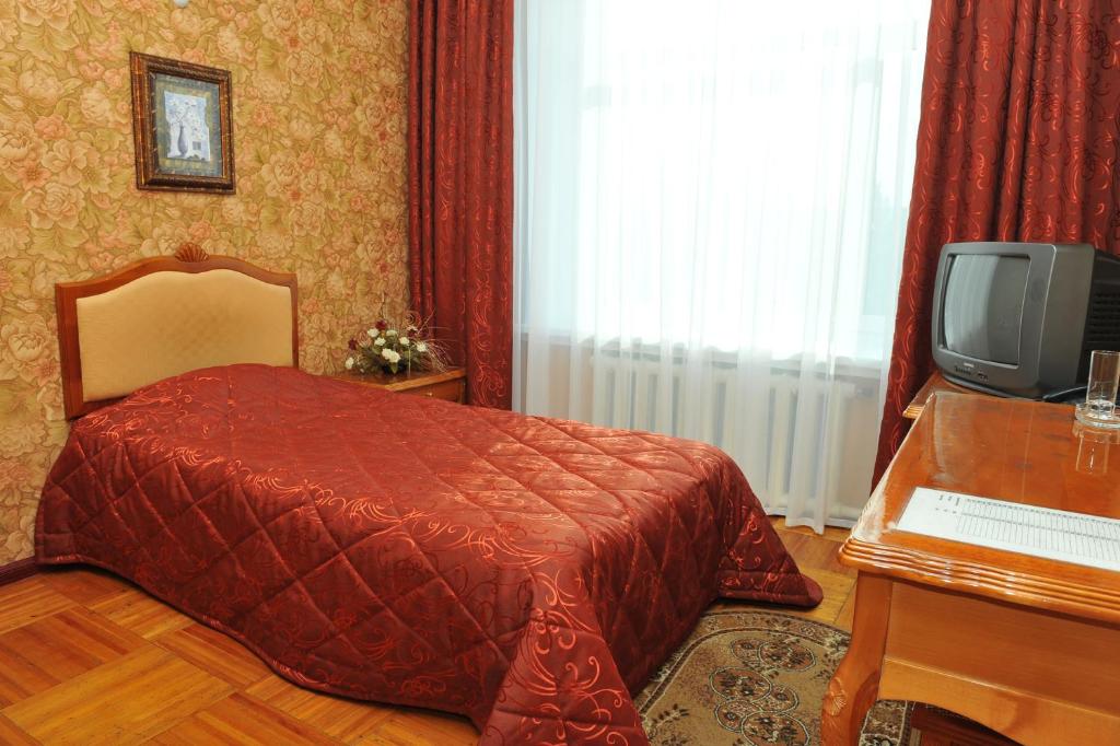 um quarto com uma cama e uma televisão em Gostinichny Komplex Germes em Karaganda