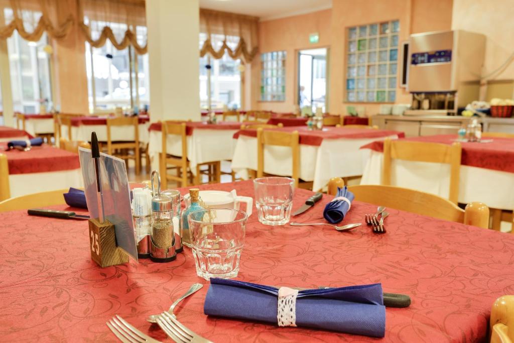 une table avec un tissu de table rouge avec des fourchettes et des verres dans l'établissement Hotel Smile, à Rimini