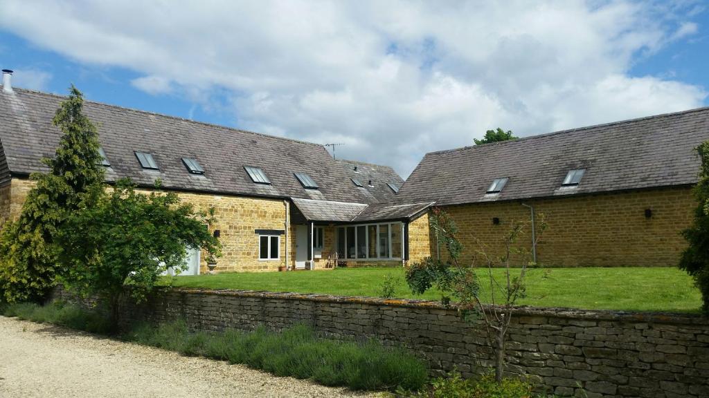 a brick house with a stone wall and a building at Greenhill Farm Barn B&B in Sutton under Brailes