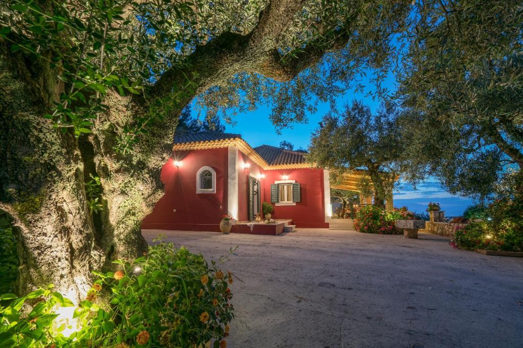 una casa rossa con un albero di fronte di Aelia Villa a Kallithea