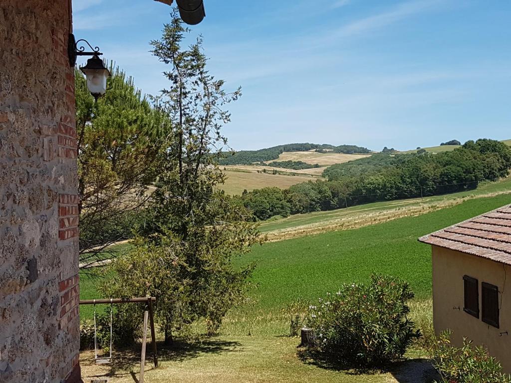 a tree sitting next to a building with a green field at Locanda il Boschetto in Volterra