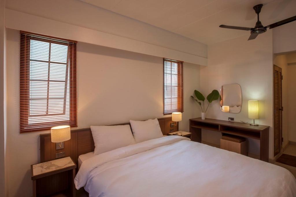 een slaapkamer met een groot wit bed en ramen bij RCN Court & Inn in Chiang Mai
