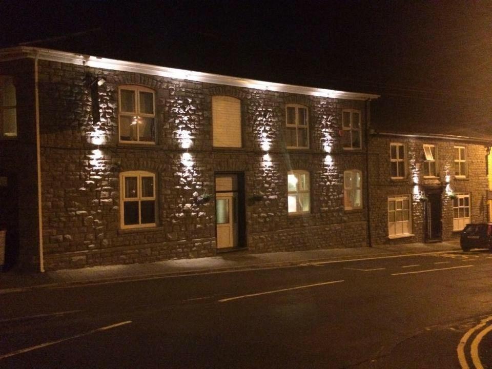 um edifício de tijolos com luzes acesas à noite em Dunraven Hotel em Rhondda